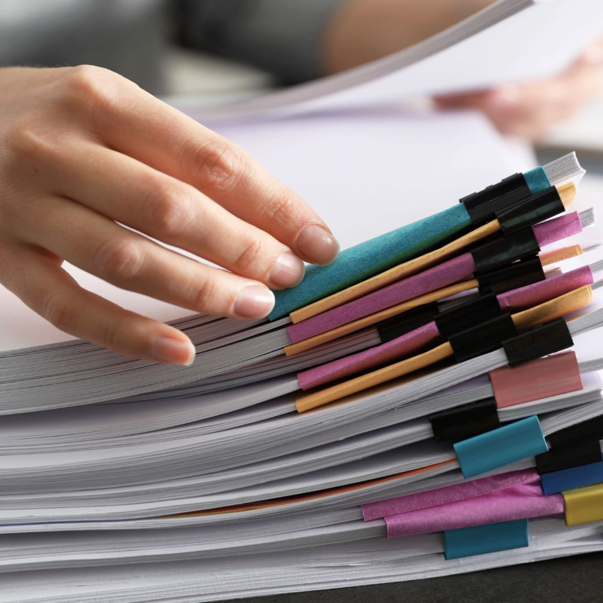 photo of a tall stack of documents with colorful binder clips.