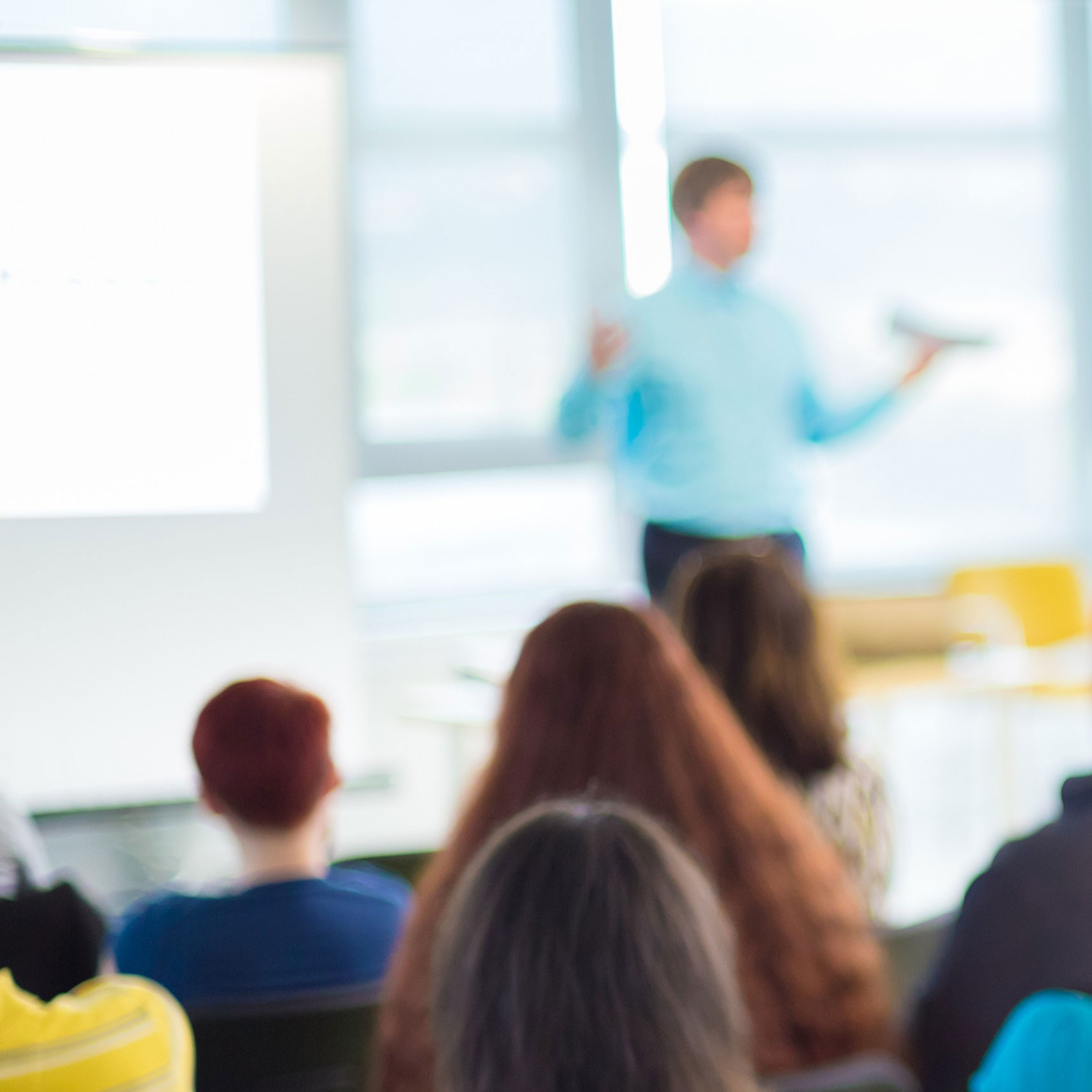 blurred photo of audience watching a presenter.